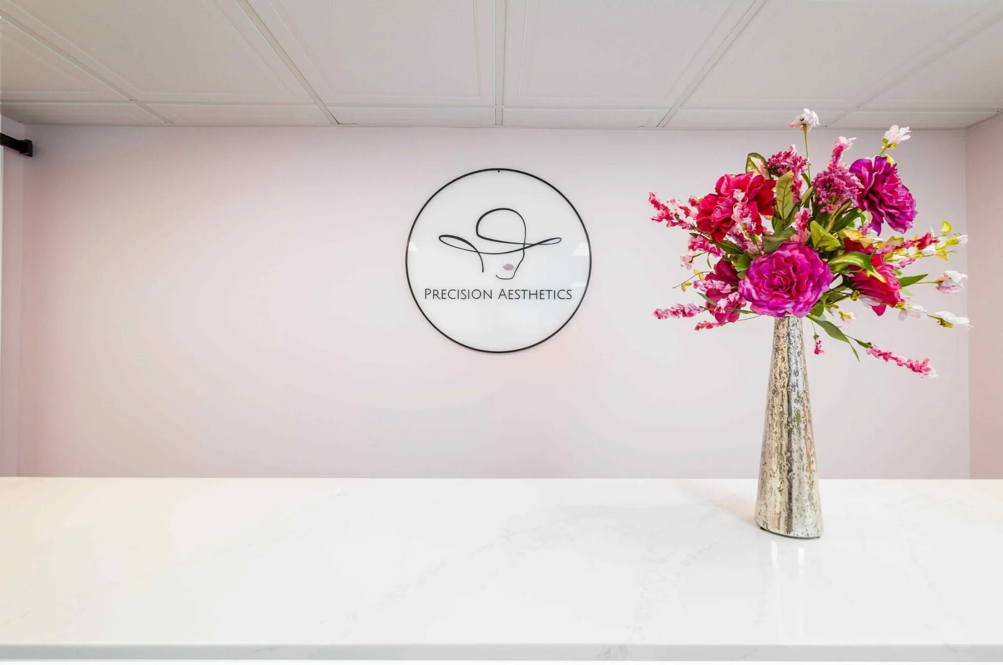 Precision Aesthetics logo wall with fresh flowers